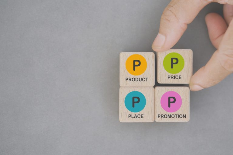 Someone showing what the four Ps of marketing is by aligning wooden cubes with the definition on them