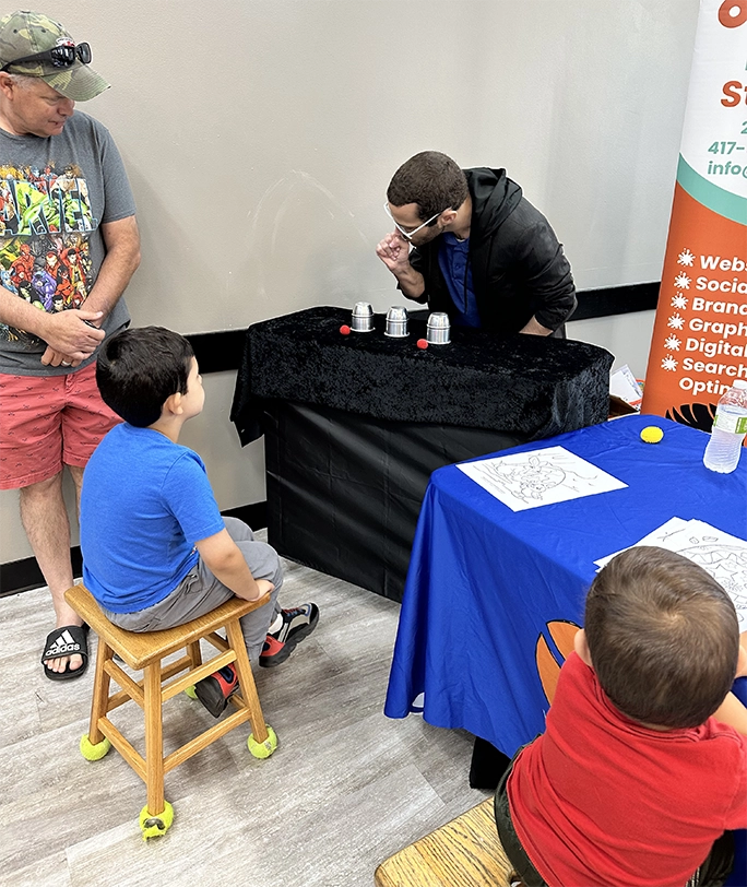 Discovery Center Easter Egg Hunt - Gabriel Cassady performing magic at the 2oddballs event sponsor table.
